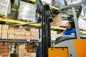 worker distributing goods in a warehouse with forklift truck loader
